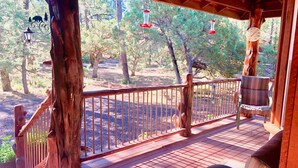 A wooden deck with a railing, a chair, and a hanging lantern. - Majestic Mountain Getaway - Jenson's TreeHouse, a Spacious Cabin Retreat. (Show Low)