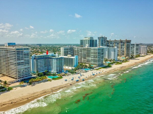 Un hotel costero con varios edificios de gran altura, una playa de arena y una vista despejada del océano.