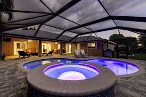 A swimming pool with a hot tub and lounge chairs, surrounded by a covered patio area. - Pool Table, Bicycles, Pool & Spa --ESCAPE - Caribbean Getaway - Roelens Vacations (Cape Coral)