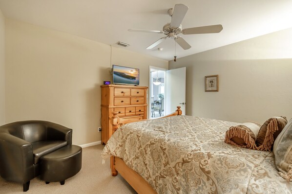 A bedroom with a bed, a ceiling fan, a wooden dresser, and a TV. - Pool Table, Bicycles, Pool & Spa --ESCAPE - Caribbean Getaway - Roelens Vacations (Cape Coral)