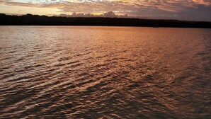 A sunset over a calm body of water with a silhouette of a forest in the background. - Absolute Beachfront  villa with private beach (Luganville)