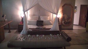 A bedroom with a four-poster bed, a bedside table, a nightstand, and a large mirror on the wall. - Absolute Beachfront  villa with private beach (Luganville)