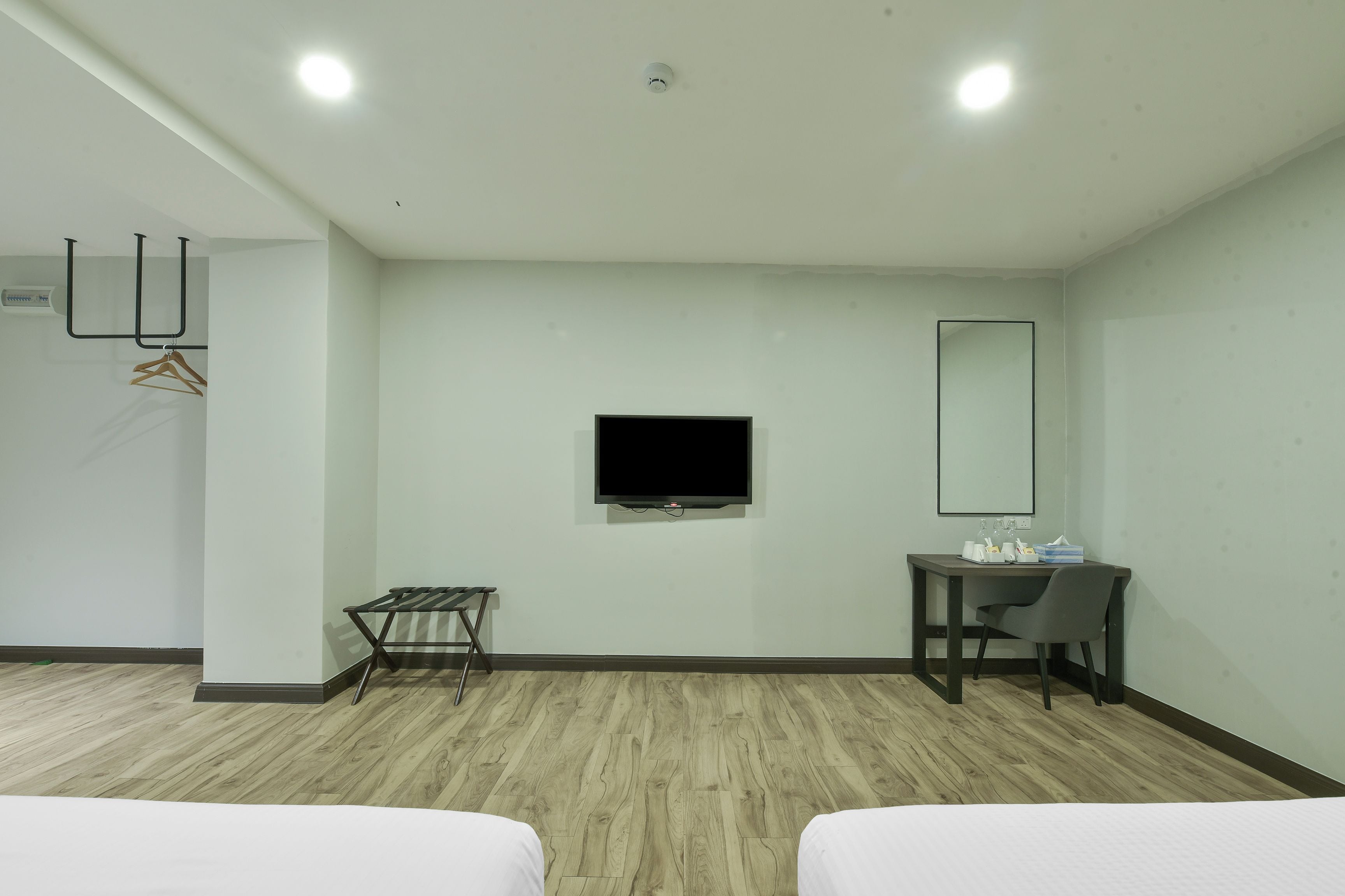 Una habitación de hotel con cama, escritorio, silla, televisor y espejo.