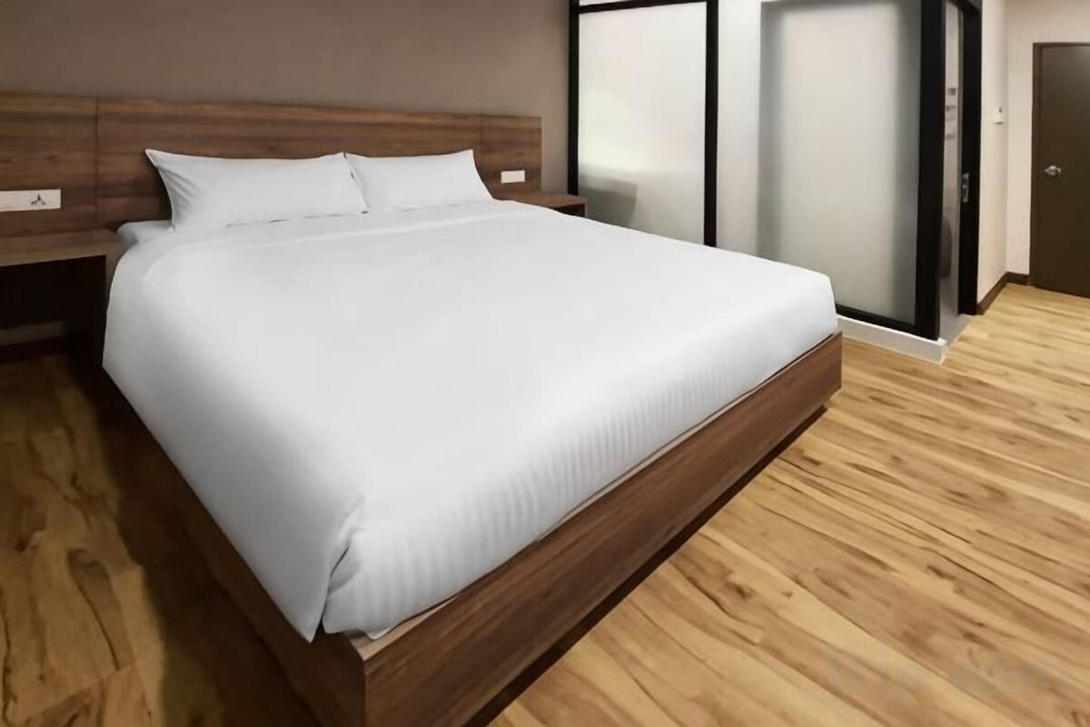 A large bed with a wooden frame and white bedding in a room with wooden flooring and a modern design.
