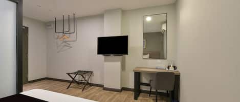 Una habitación de hotel con una cama, un escritorio, una silla, un televisor y un espejo.
