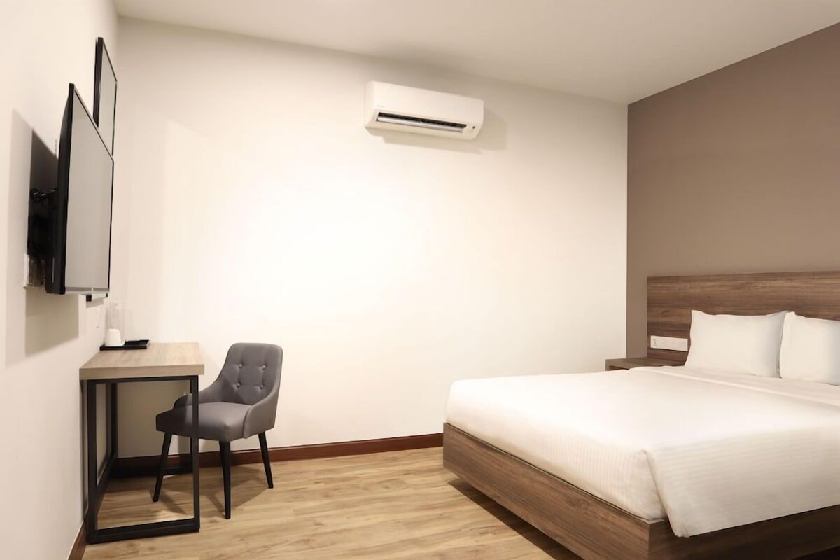 A modern hotel room with a bed, a desk, a chair, and an air conditioning unit.
