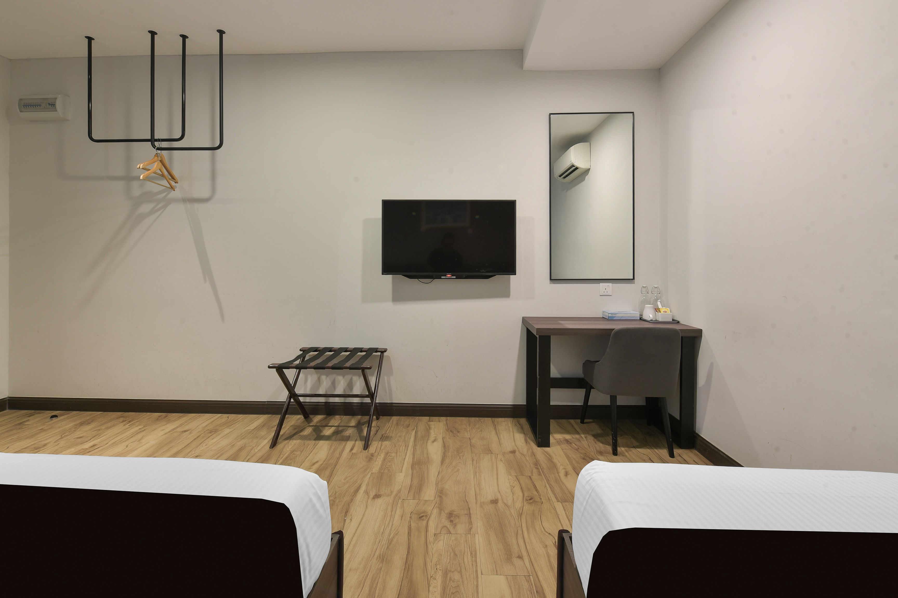 Une chambre d’hôtel avec deux lits, un bureau, une télévision et un miroir.
