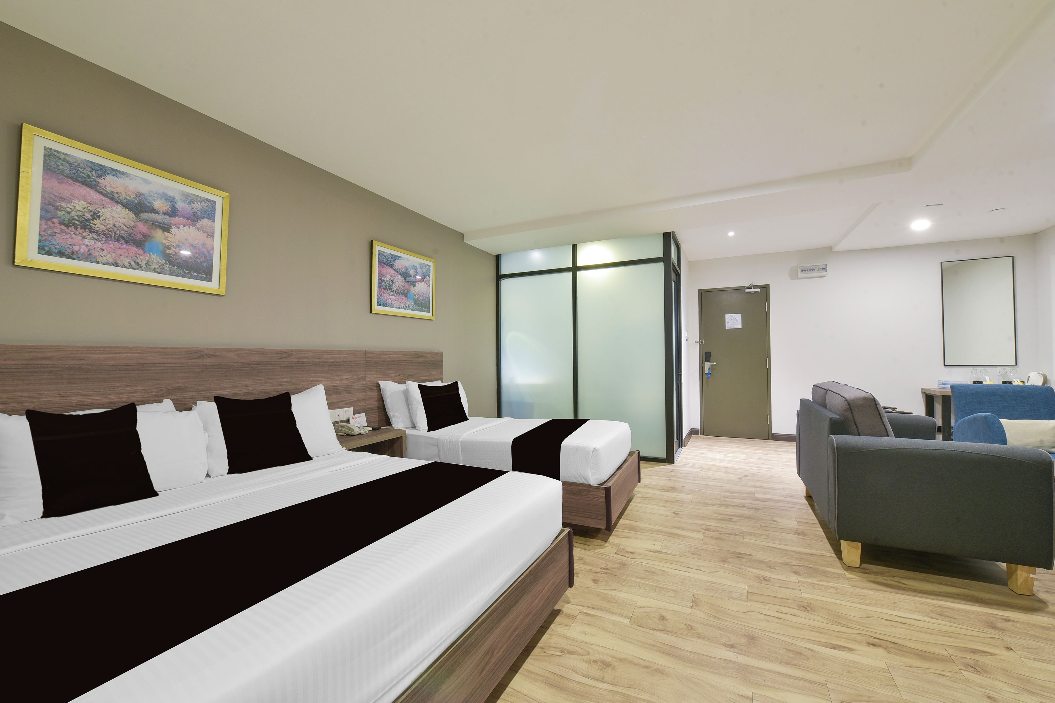 A hotel room with two beds, a desk, a chair, and a large mirror.