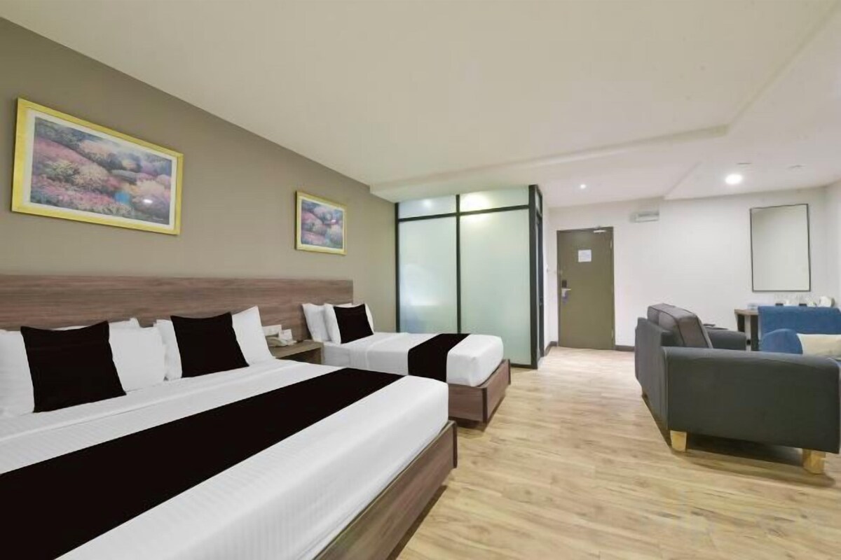 A hotel room with two beds, a sofa, a desk, and a large window.