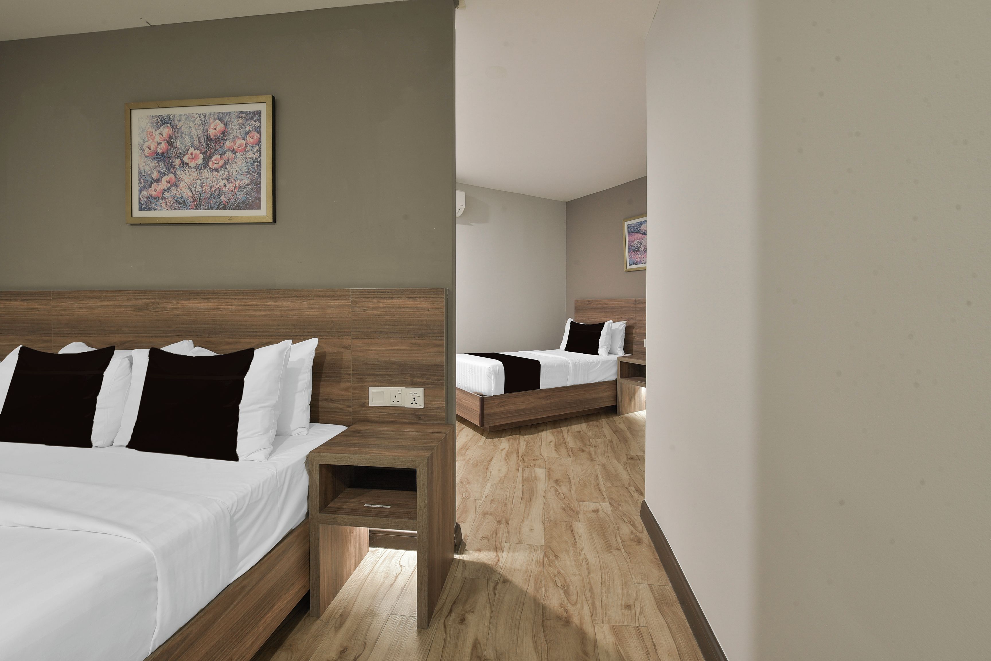 Habitación de hotel con dos camas, cabecera de madera, mesita de noche y un cuadro en la pared.