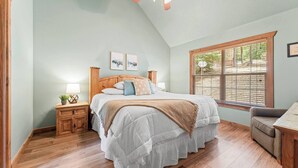 A bedroom with a wooden bed, a nightstand, a chair, a window with blinds, and a ceiling fan. - Rustic Stonebridge Cabin, near Silver Dollar City Pools>Golf>Lake>Nature (Branson West)