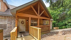 A wooden cabin with a stone exterior, a front porch, and a door with a wreath. - Rustic Stonebridge Cabin, near Silver Dollar City Pools>Golf>Lake>Nature (Branson West)