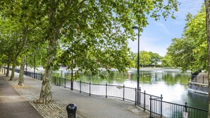 A riverside walkway with a paved path, metal railing, and trees. - One Bedroom Lush Apartment Next to Wembley Stadium (Wembley Park)