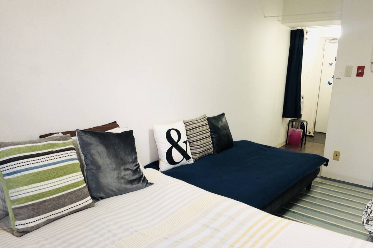Une chambre d’hôtel avec un lit, des oreillers, un tapis à rayures et une porte donnant sur une autre pièce.
