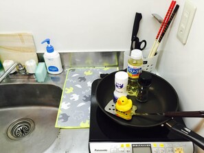 A kitchen with a Panasonic induction cooktop, a yellow rubber duck, a bottle of oil, and a bottle of vinegar. - Best Apartment in Shinjuku (Tokyo)