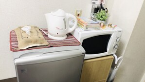 Une petite cuisine équipée d’un réfrigérateur, d’un four à micro-ondes et d’une bouilloire.