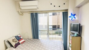 Une chambre à coucher avec un lit, une télévision et une fenêtre avec des rideaux.