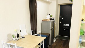 Une cuisine de taille réduite avec une table en bois, des chaises blanches, un réfrigérateur et un évier.