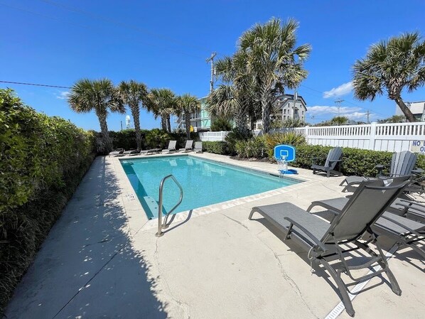 A swimming pool with lounge chairs and a white fence. - Young and Restless - Oceanfront in Garden City Beach (Garden City)