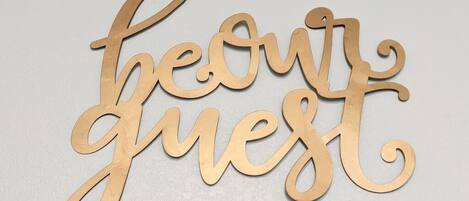A wooden sign with the words "be our guest" in cursive lettering.
