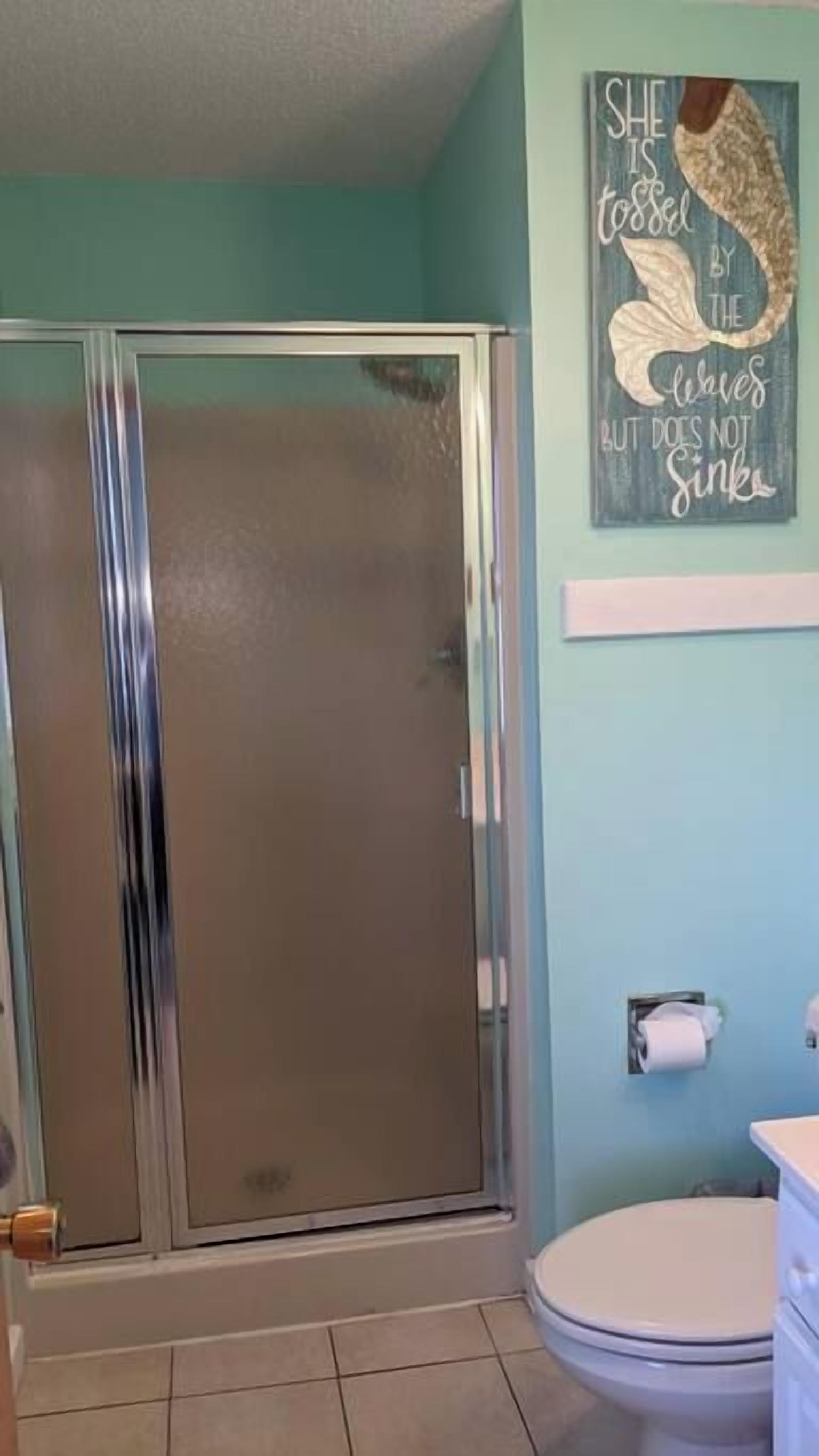 A bathroom with a glass shower enclosure, a toilet, and a wall-mounted towel rack.