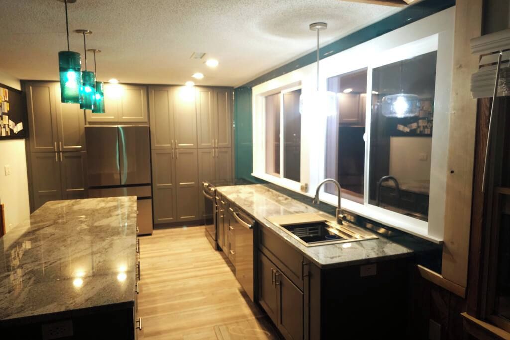 A modern kitchen with a marble countertop, stainless steel appliances, and a large window providing natural light.