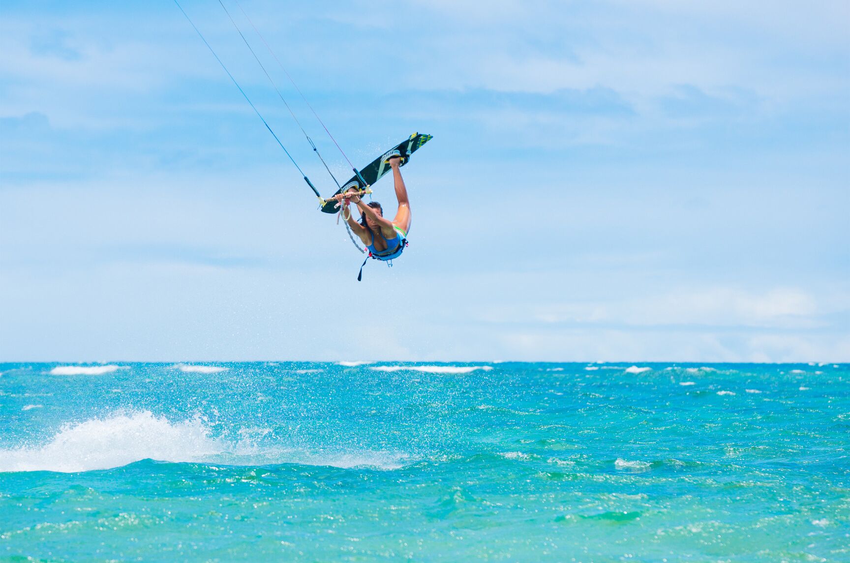 A person kiteboarding over turquoise water.
