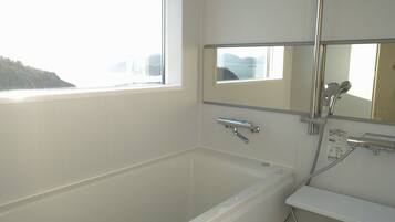 Une salle de bain avec une baignoire, une douche, une fenêtre et un miroir.