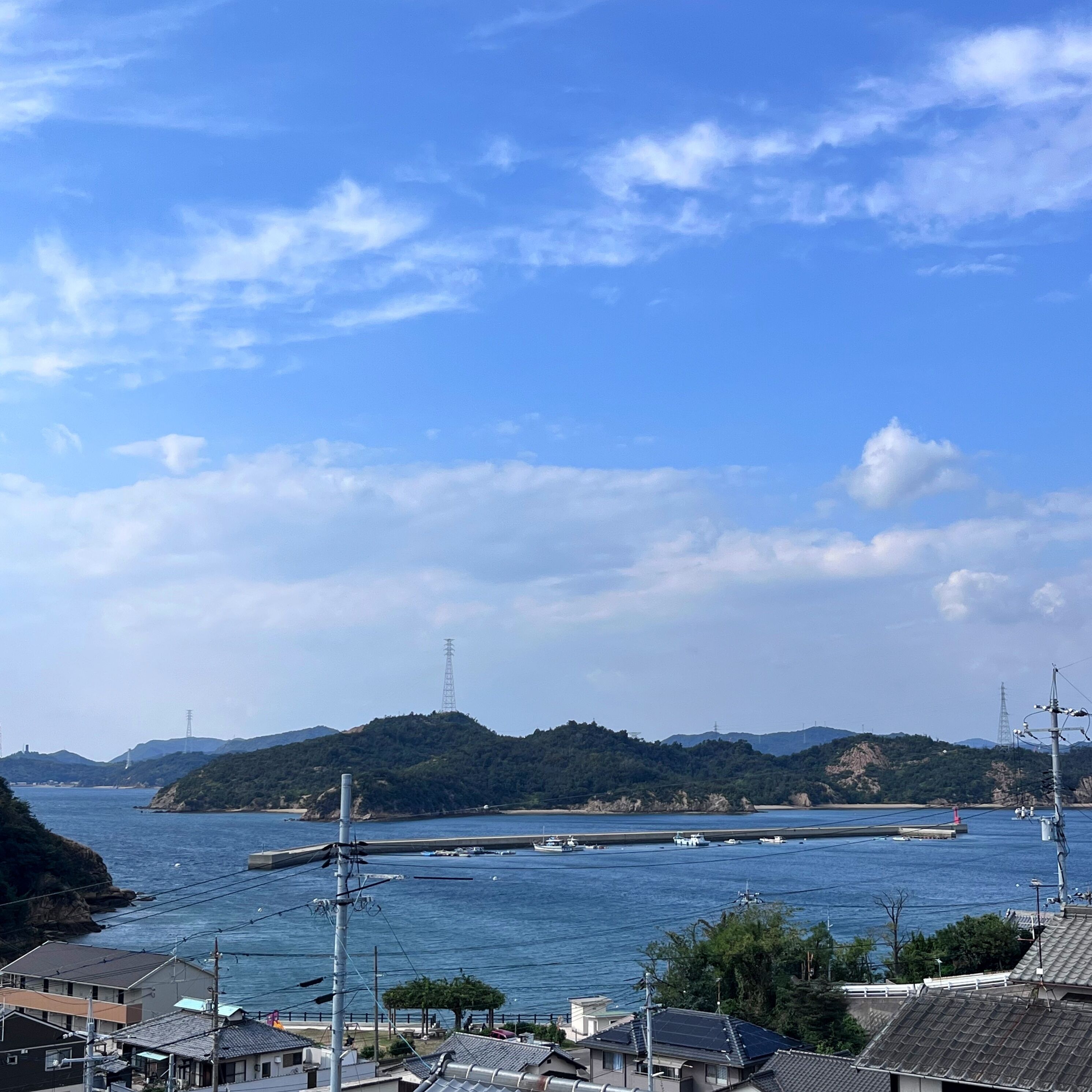 A coastal town with a bridge over water, buildings with traditional architecture, and hills in the background.