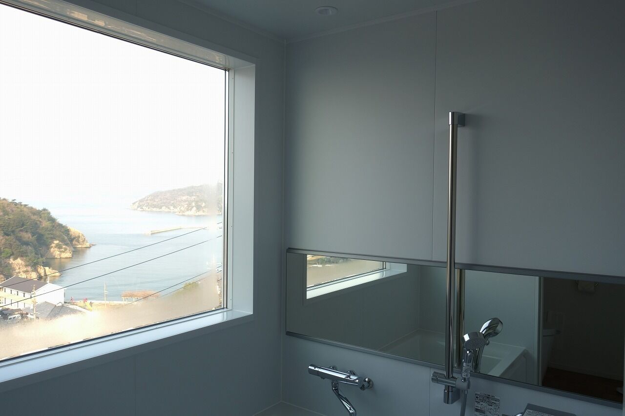 A bathroom with a large window, a mirror, and a shower.