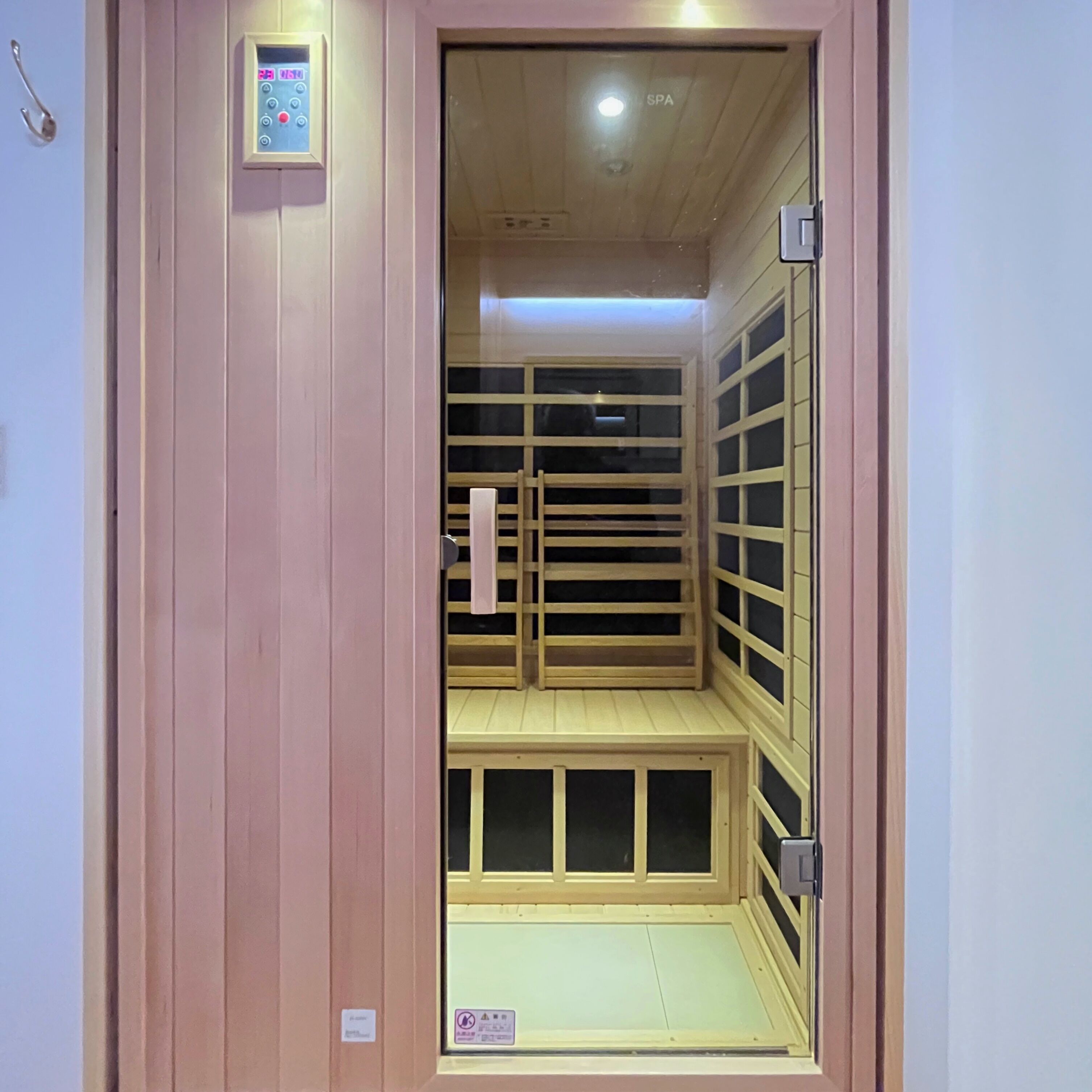 Una sala de sauna con bancos de madera y un panel de control en la pared.