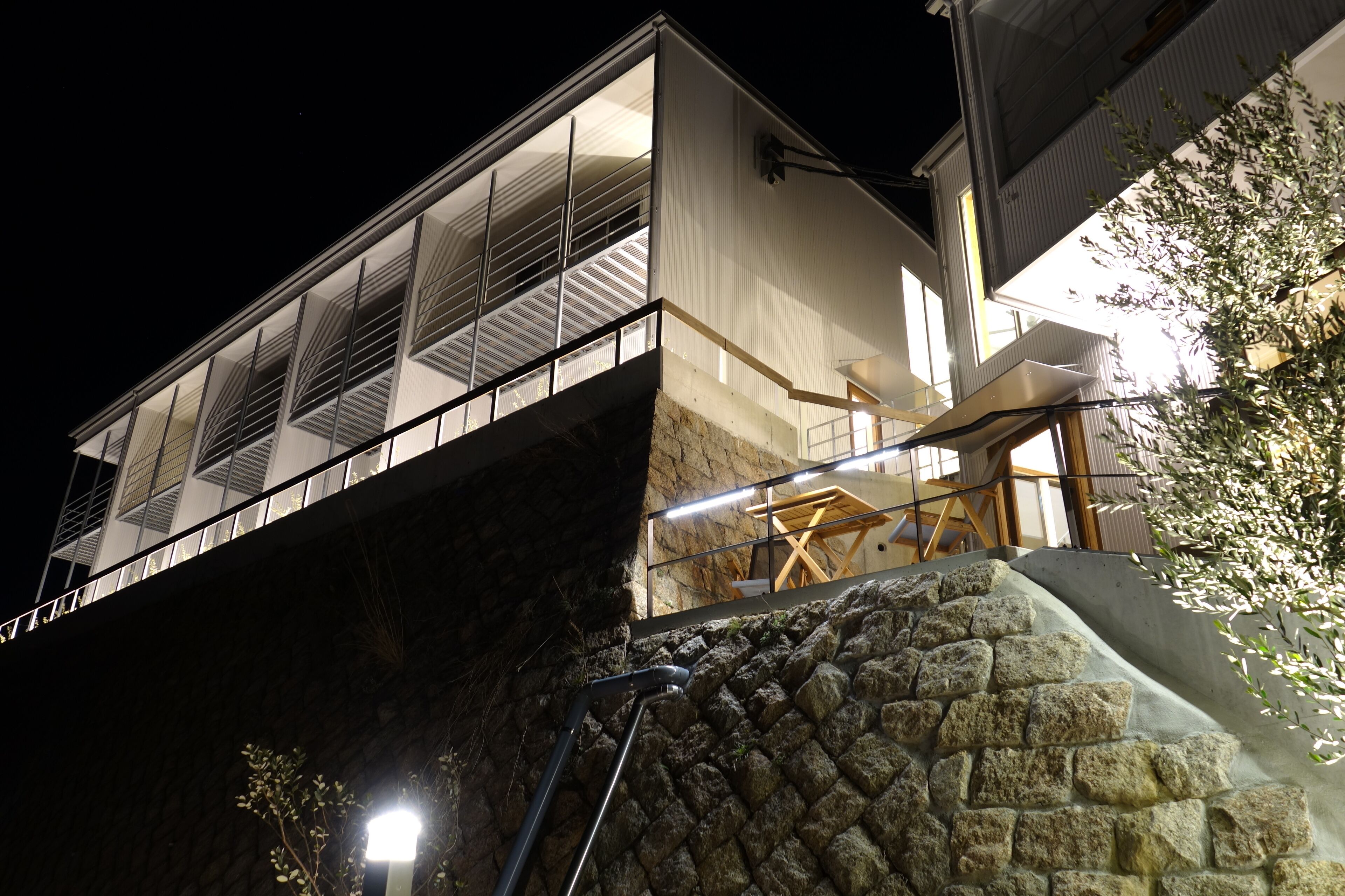 A modern building with a stone facade, a balcony with railings, and a staircase leading to an upper level.