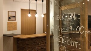 Un comptoir d’accueil avec un plan de travail en bois et un mur en verre indiquant les heures d’arrivée et de départ.