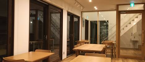 A modern interior with wooden tables and chairs, glass doors, and a staircase.