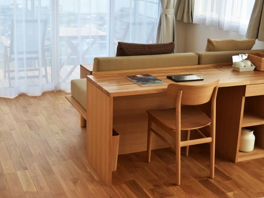 Een moderne, goed verlichte kamer met een houten bureau, een comfortabele bank en uitzicht door grote ramen.