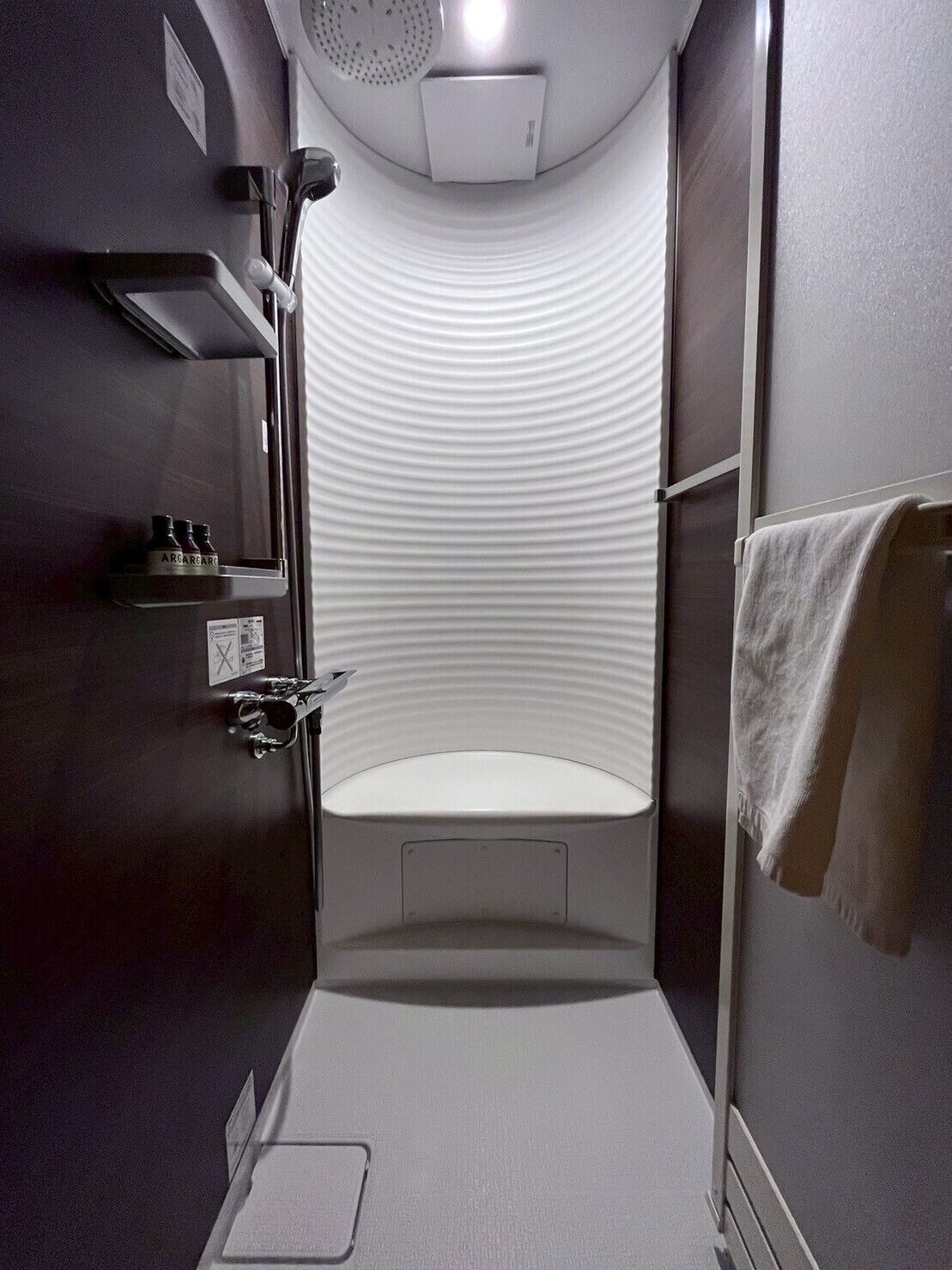 A small, modern bathroom with a shower, a toilet, and a sink.