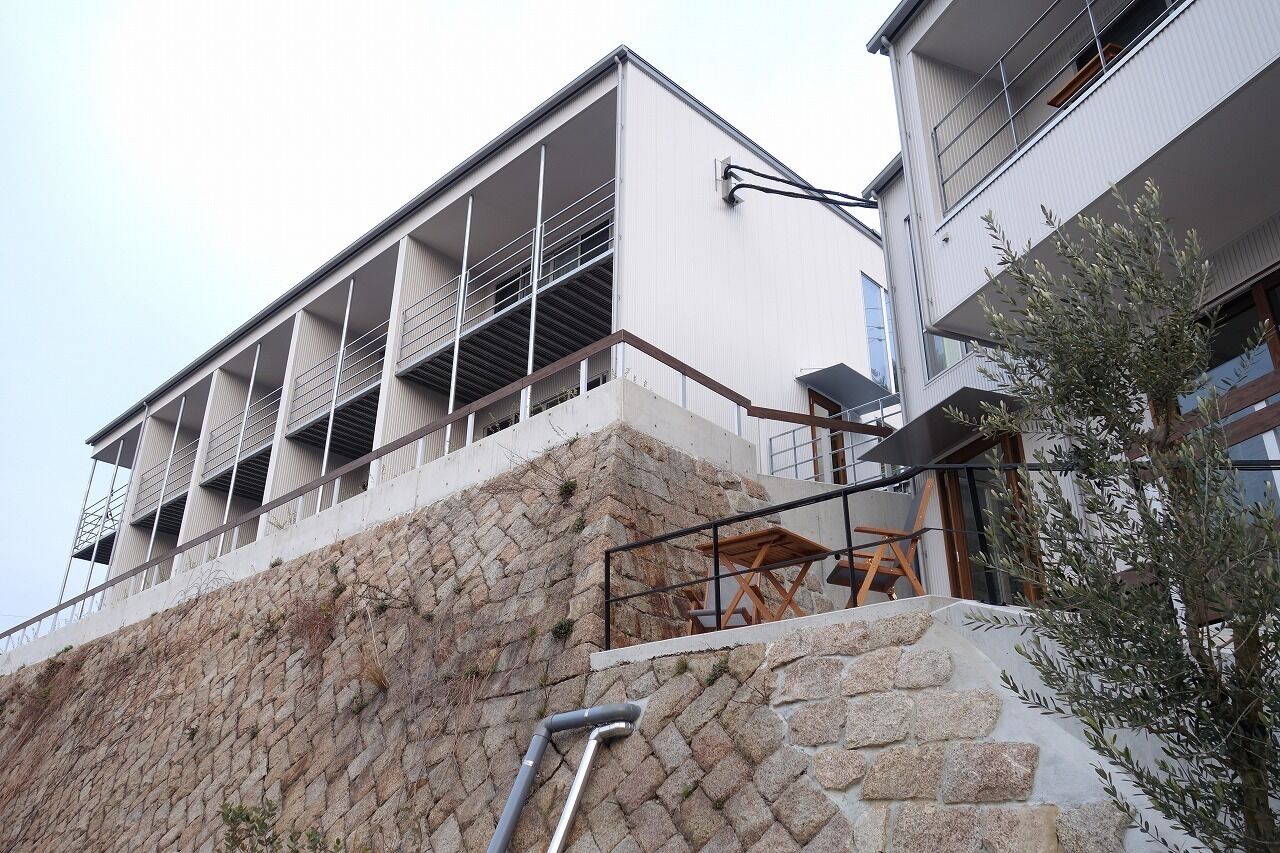 A modern building with a stone facade, balconies, and a staircase leading to an upper level.