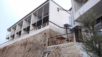 A modern building with a stone facade, balconies, and a staircase leading to an upper level.