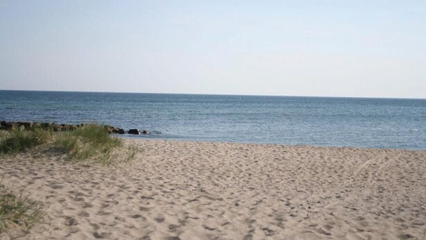 Une plage de sable fin, avec une mer calme et un ciel dégagé.