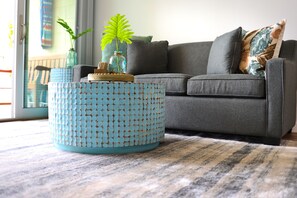 A living room with a grey sofa, a patterned blue coffee table, a potted plant, and a striped rug. - Oceanfront, Exceptionally Remodeled, Split A/C, King bed, OH the sunsets (Kihei)