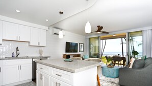 A modern kitchen with white cabinetry, a central island, and pendant lighting. - Oceanfront, Exceptionally Remodeled, Split A/C, King bed, OH the sunsets (Kihei)