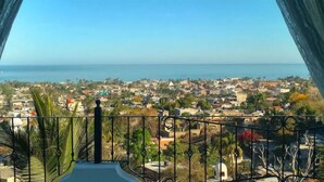Ein Balkon mit Blick auf eine Küstenstadt und das Meer.