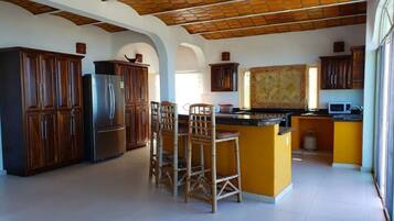 A spacious kitchen with wooden cabinets, a stainless steel refrigerator, and a central island with bar stools.