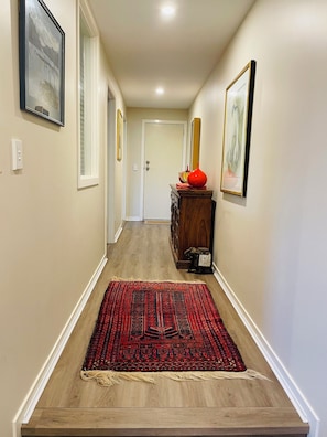 Stunning hallway with a beautifully designed entrance, featuring a patterned rug and framed artworks.
