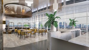 Un restaurante moderno con ventanas amplias, vistas a la ciudad y una planta en el centro.