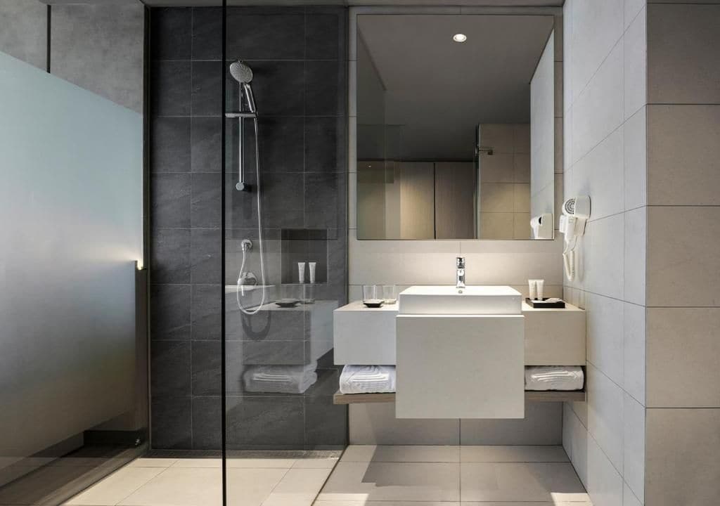 A modern bathroom with a glass shower enclosure, a white sink, and a mirror.