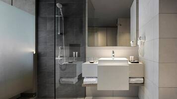 A modern bathroom with a glass shower enclosure, a white sink, and a mirror.