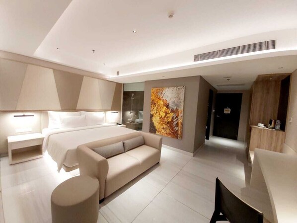 Un dormitorio moderno con cama, sofá, escritorio y un cuadro abstracto grande.