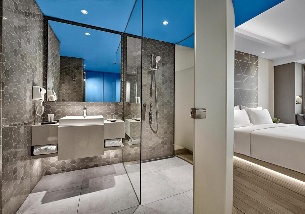 A modern bathroom with a glass-enclosed shower, a large mirror, and a separate vanity area.