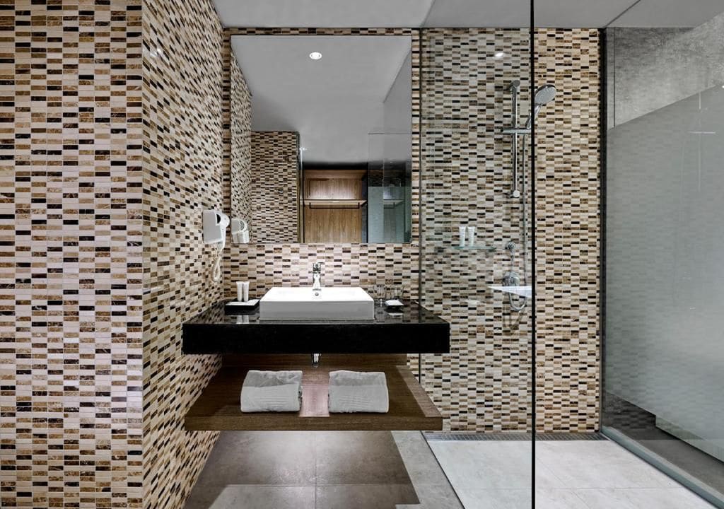 A modern bathroom with a tiled backsplash, a freestanding sink, and a glass shower enclosure.